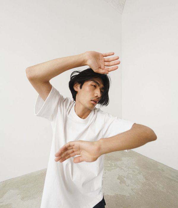 Person in a dynamic yet calm pose in a minimalist space.
